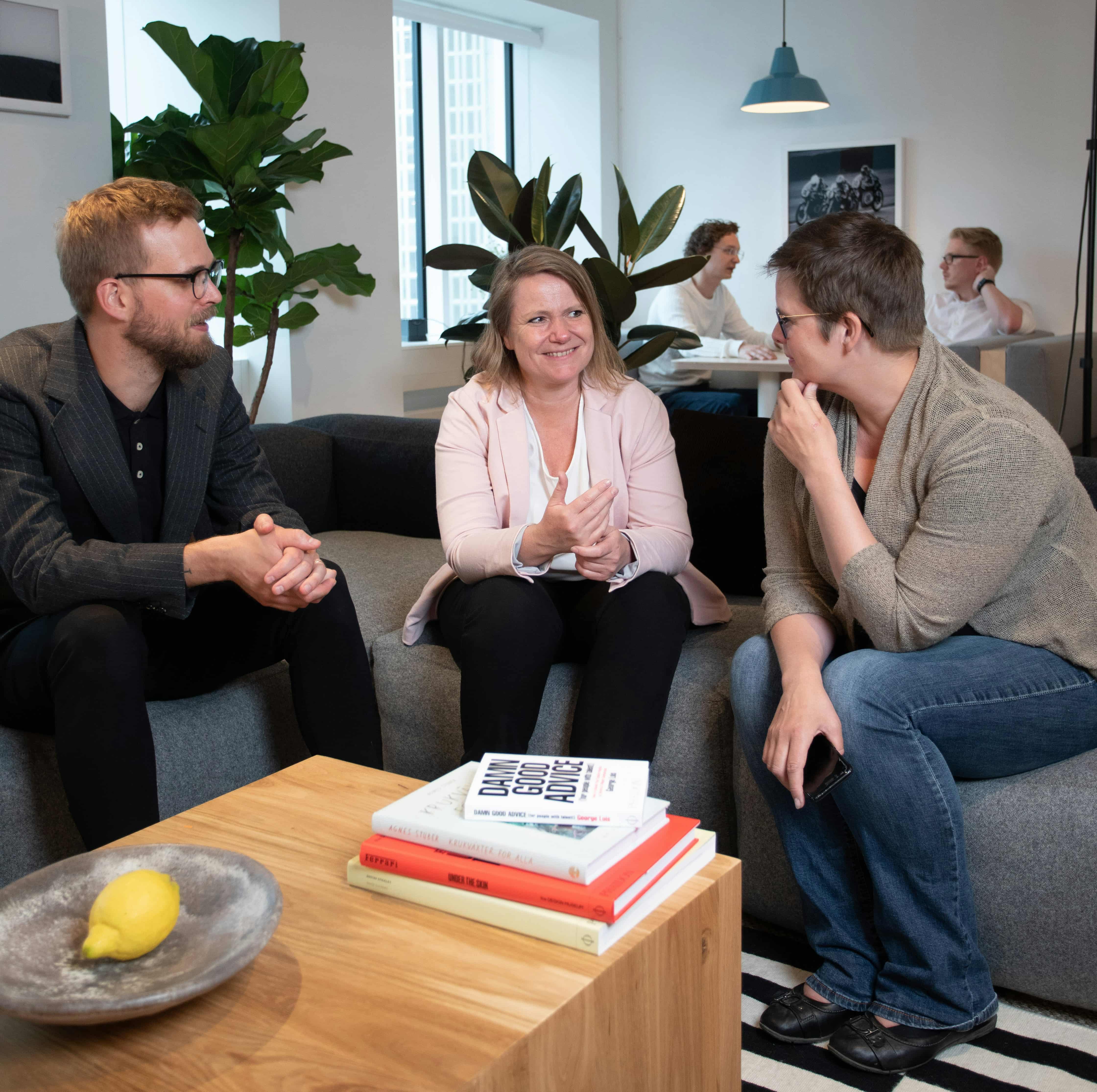 Grupo diverso de personas sonrientes interactuando en un entorno acogedor, simbolizando coaching y desarrollo personal